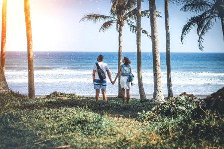 Man And Woman Holding Hand Near Beach Shore Under Sunny Sky