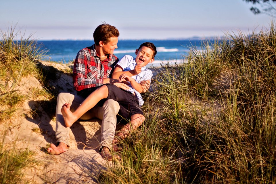 Man And Boy Sitting On Floor Near Body Of Water