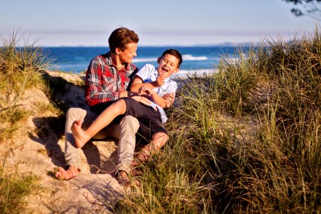 Man And Boy Sitting On Floor Near Body Of Water