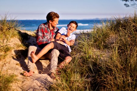 Man And Boy Sitting On Floor Near Body Of Water photo