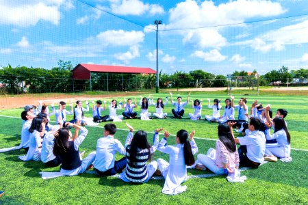 People Sitting On Green Lawn Grass While Doing Hands Up At Daytime photo