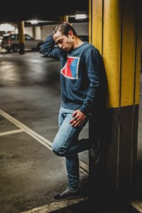 Man Leaning On Yellow And Gray Metal Post photo