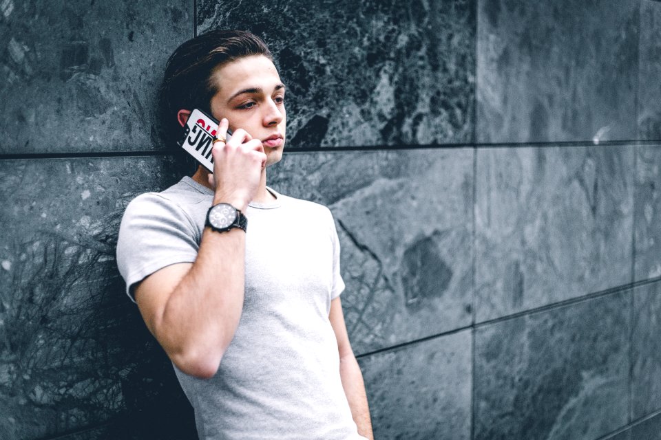 Man Wearing Gray Crew-neck T-shirt Leaning On Gray Wall