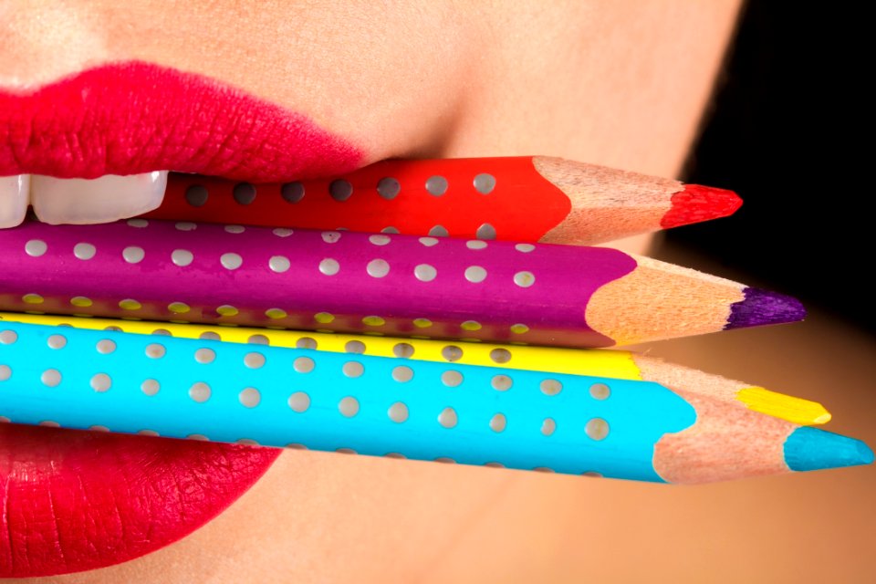 Woman Biting Three Color Pencils