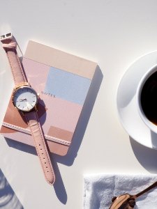 Round Gold-colored Analog Watch With Pink Leather Strap On Pink Notebook