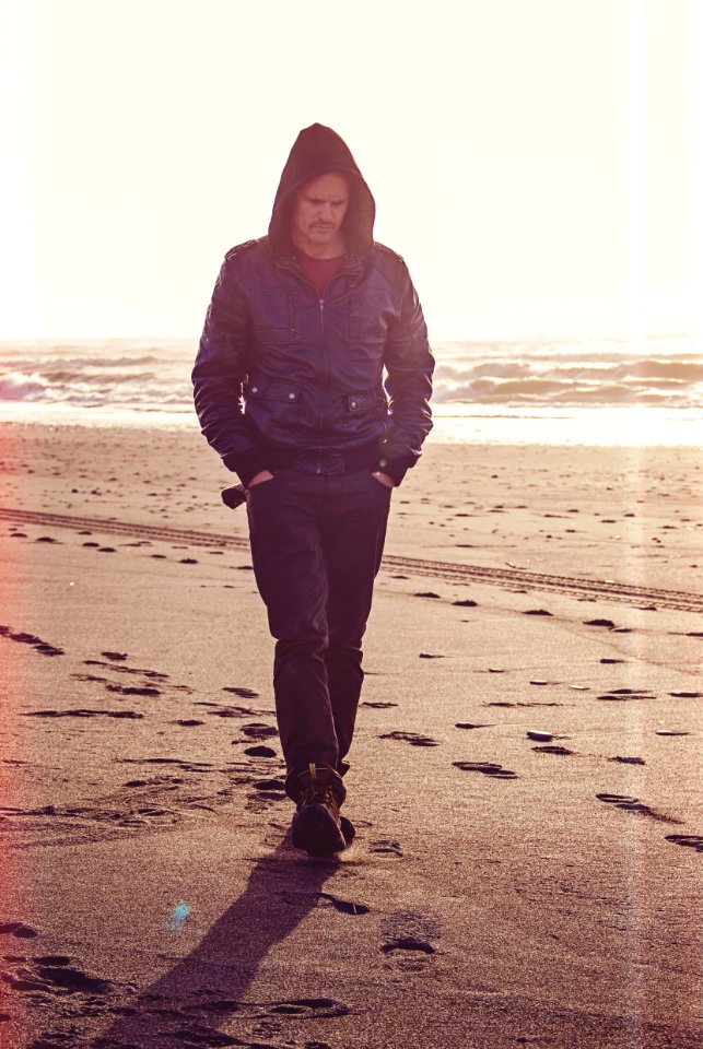 Man Walking On Beach Wearing Black Leather Coat photo