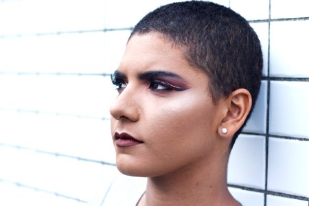 Woman Wearing Stud Earrings Leaning White Tiled Wall photo