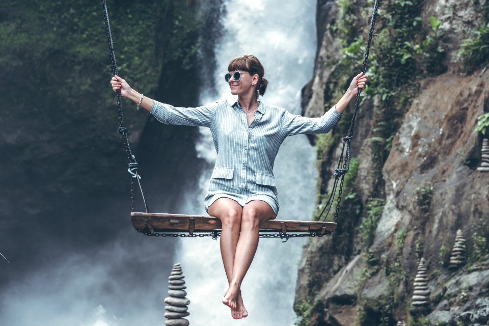 Photo Of Woman Riding Swing In Front Of Waterfalls