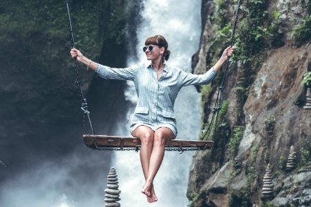 Photo Of Woman Riding Swing In Front Of Waterfalls