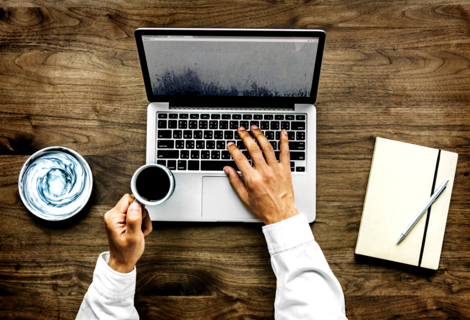 Person Holding Black Ceramic Cup And Macbook Pro