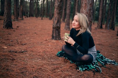 Woman In Black Sweater Sitting On Brown Ground While Holding Cup photo