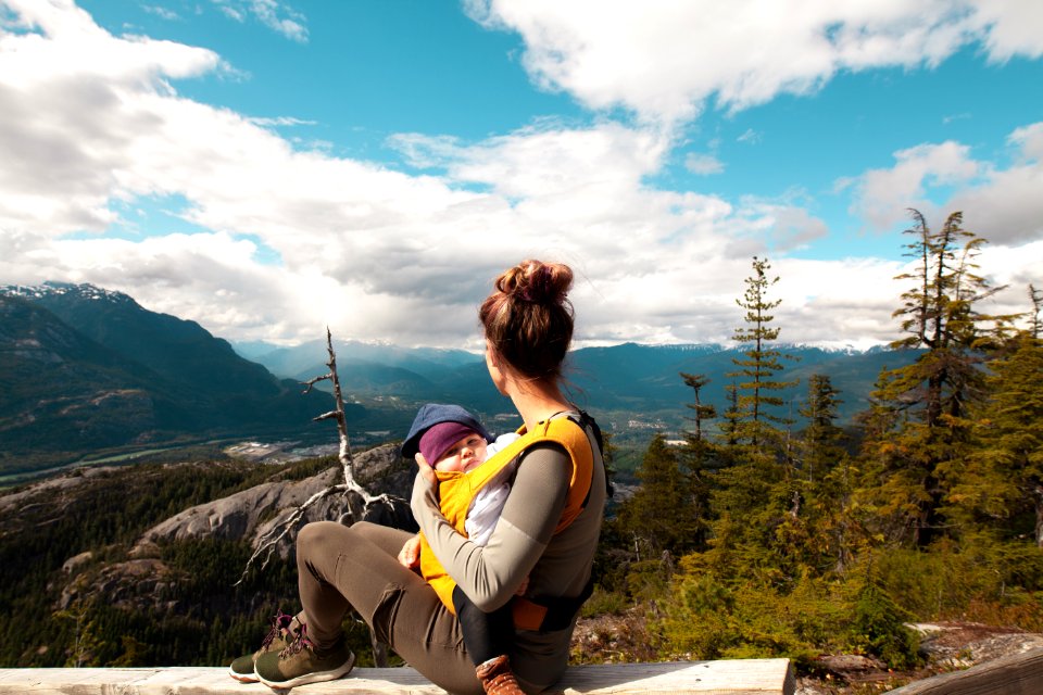 Woman Carrying Baby Sitting On Gray Surface