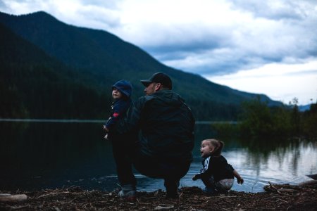 Man With Two Kids Near Body Of Water photo