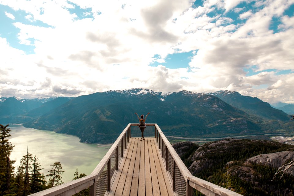 Person Standing With Hands On Air On Brown Wooden Dock With Overlooking View Of Lake Under White Clouds And Blue Sky photo