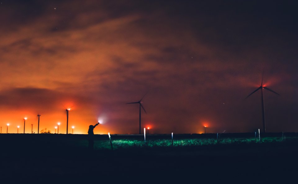 Photography Of Person Holding Flashlight Near Windmills During Night Time