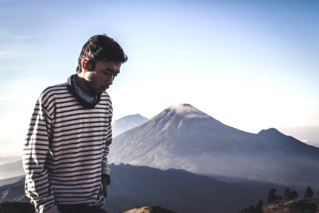 Person Wearing White And Black Striped Sweatshirt Standing In Front Of Mountains photo