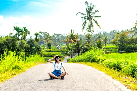 Tropical Portrait Of Young Happy Woman With Straw Hat On A Road With Coconut Palms And Tropical Trees Bali Island