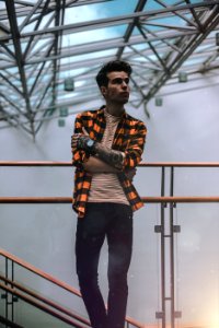 Man Standing On Brass Railing Looking Sideways