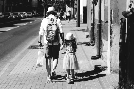Man Holding Girl While Walking On Street photo