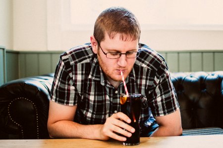 Man Sipping Drink From Clear Glass