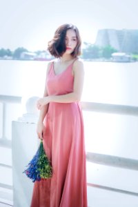 Woman Wearing Pink Spaghetti Strap Maxi Dress Holding Flowers photo