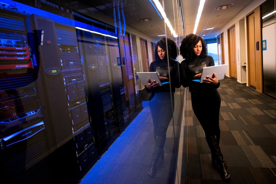 Woman Holding Laptop Beside Glass Wall