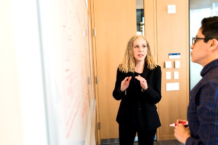 Woman Wearing Suit Jacket Standing In Front Of Whiteboard