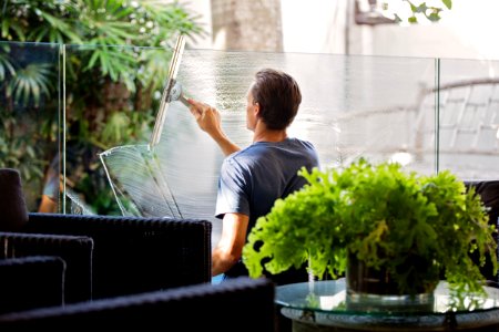 Man In Gray Shirt Cleaning Clear Glass Wall Near Sofa photo