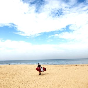 Person Holding Red And White Surfboard Near Sea Under Blue Sky photo