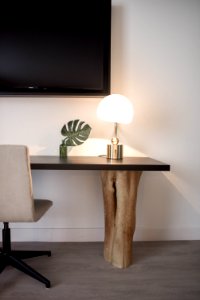 Stainless Steel Base White Shade Table Lamp On Brown Wooden Desk Near White Painted Wall With Wall Mounted Flat Screen T V photo