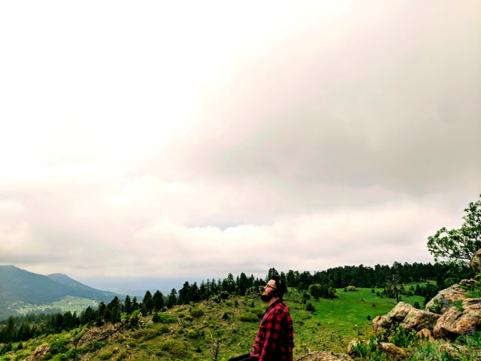 Man Wearing Red And Black Plaid Shirt Standing On Green Grass Hill photo