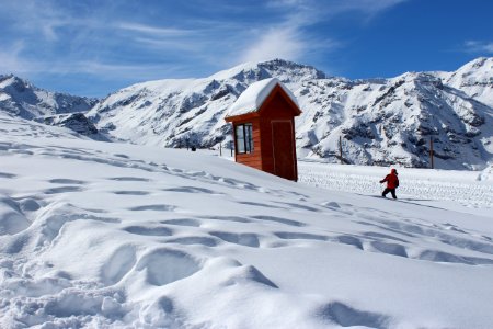 Photo Of Person In Red Coat Near Brown House In Snow photo