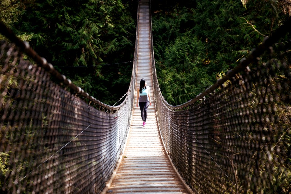 Woman Wearing Blue Sleeveless Shirt Walking On Bridge At Daytime