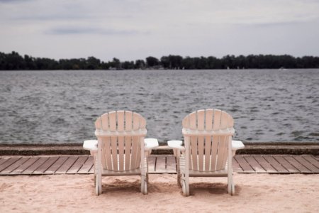 Two White Lounge Chairs Beside Body Of Water photo