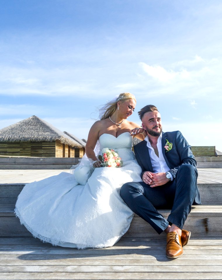 Woman Wearing White Wedding Gown Sitting Near Man Wearing Black Suit Jacket And Pants