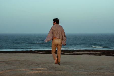 Man Walking Towards Shore With Grey Towel On Back photo