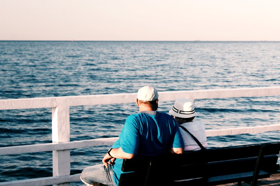 Man In Blue Shirt Beside Woman In White Shirt Sitting On Bench