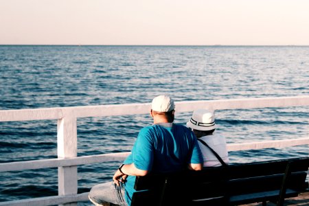 Man In Blue Shirt Beside Woman In White Shirt Sitting On Bench photo