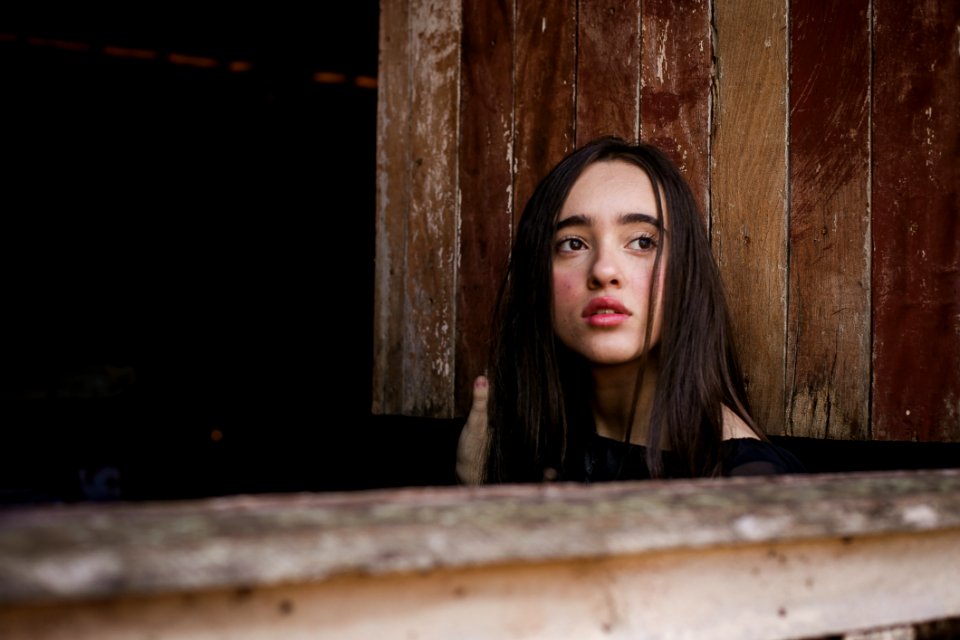 Selective Focus Photography Of Woman In Front Of Brown Wooden Wall