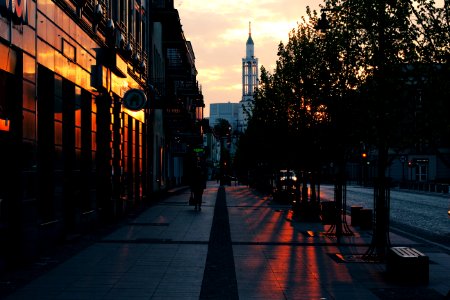 Person Walking On Gray Pavement Near Buildings During Golden Hour photo