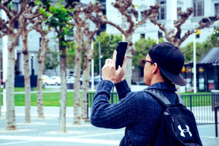 Man Wearing Black Jacket And Holding Black Android Smartphone photo