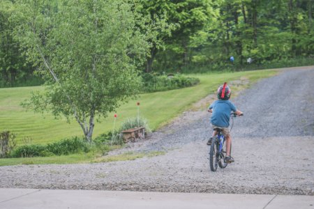 Boy Wearing Blue T-shirt And Beige Shorts Outfit Riding On Black Bicycle At Daytime