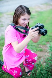 Shallow Focus Photo Of A Girl In Pink Round-neck Shirt Holding Black Dslr Camera photo