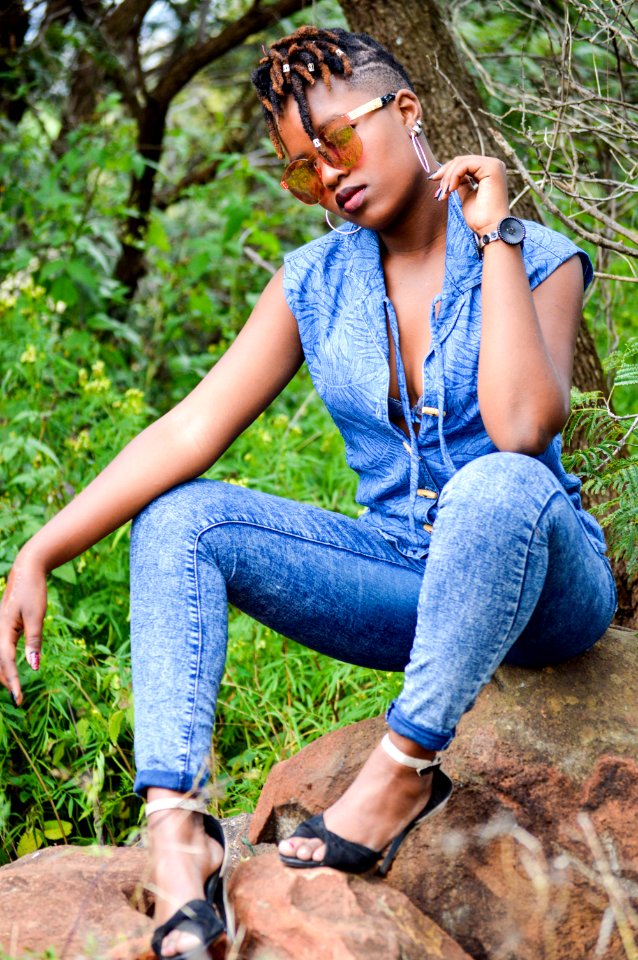 Woman Wearing Denim Pants Sitting On Brown Stone Near Plants photo