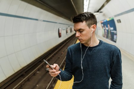 Man Looking At A Phone With Earphones On photo