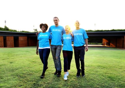 Four People Wearing Blue Crew-neck Shirts Standing On Lawn
