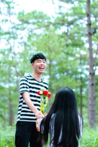 Man Wearing White And Black Striped Crew-neck Shirt Holding Red And Yellow Flowers