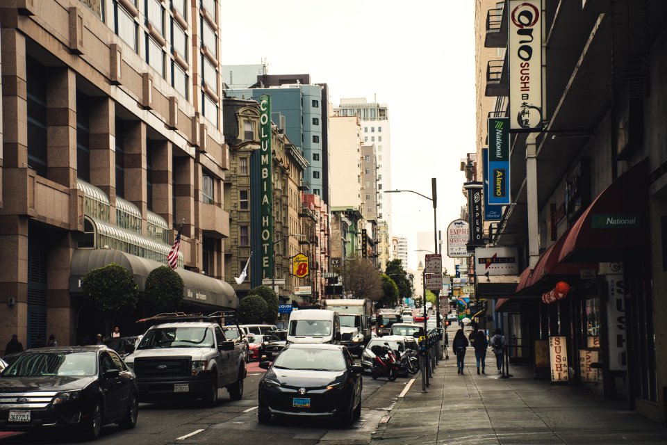 Busy Street With Vehicles And People Walking Beside Buildings photo