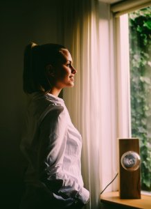 Woman Wearing White Long-sleeved Shirt Standing In Front Of The Window With White Curtain photo