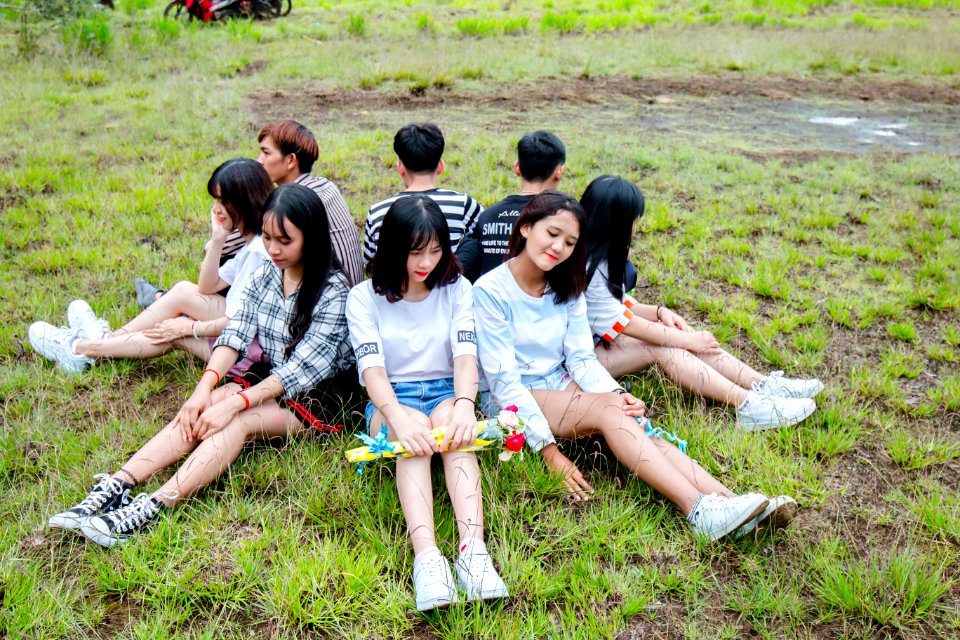 Men And Women Sitting On Grass Forming Circle Of Friends